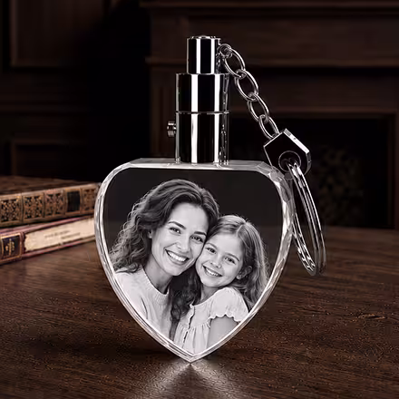 3D Crystal Heart Keychain engraved with a mother and daughter portrait, displayed with a polished metal key ring on a wooden tabletop.