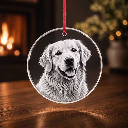 2D Crystal Round Ornament engraved with a Golden Retriever portrait, suspended from a red ribbon in a warm holiday setting.